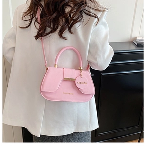 Détail d'un sac à main en cuir PU rose avec barre dorée et pendentif à la mode