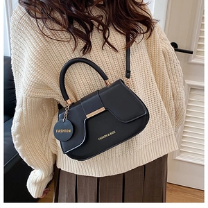 Détail du sac en cuir PU mat noir avec garnitures dorées et pendentif logo gravé
