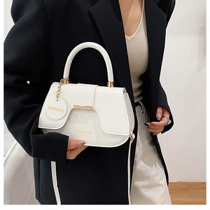 Détail du sac à main blanc en cuir avec ornements dorés et pendentif chaîne sur mannequin