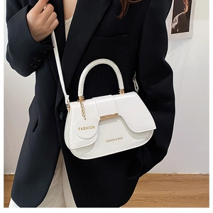 Gros plan d'un sac selle blanc avec des ferrures dorées et une médaille gravée