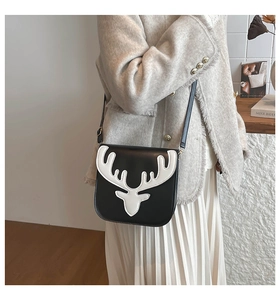 Détail du motif tête de cerf sur un sac bandoulière en cuir noir et blanc avec dorures
