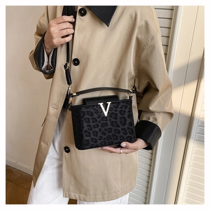 Détail du sac boîte léopard noir avec logo V porté sur un trench-coat de couleur kaki