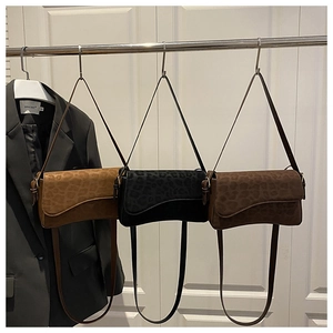 Detailed view of three suede leopard print shoulder bags in brown, black, and chocolate tones