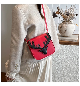 Detail of red PU leather crossbody bag with 3D reindeer design on beige knit cardigan