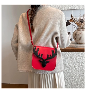 Détail du sac rouge avec gaufrage de renne noir sur un rabat en similicuir lisse