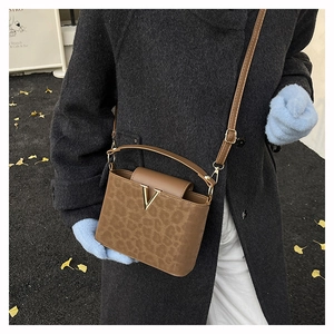 Détail du sac bandoulière léopard avec boucle en V dorée sur similicuir de couleur marron