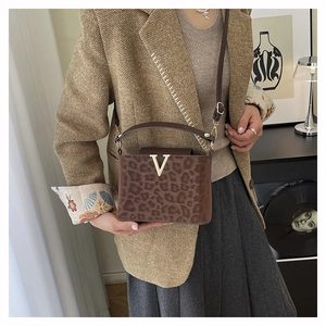 Détail du sac boîte imprimé léopard avec quincaillerie en V dorée et poignée chic