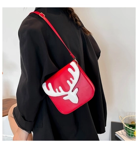 Détail du sac bandoulière en similicuir rouge avec décor renne blanc et boucle dorée