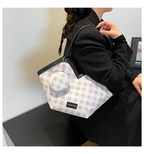 Detail showing checkered tote bag with matching round coin purse on a model shoulder