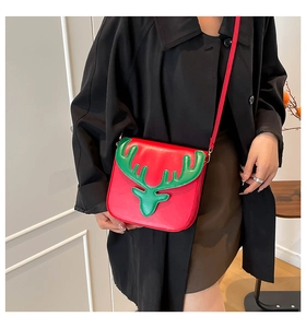 Détail d'un sac bandoulière rouge festif avec bois de renne verts sur fond de manteau noir