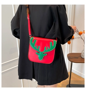 Détail du sac bandoulière de Noël rouge et vert porté sur un manteau d'hiver noir élégant