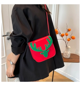 Detailed side view of a red Christmas reindeer crossbody bag worn over a black coat