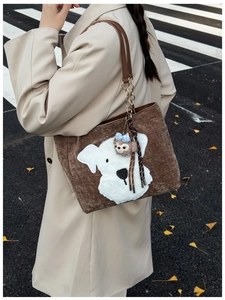 Detail of dark brown corduroy tote bag with puppy patch and plush charm on shoulder