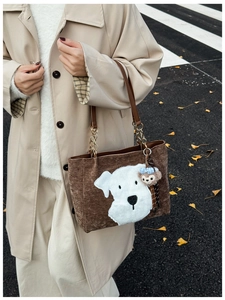 Detail of a brown corduroy tote bag featuring a cute white plush dog patch and chain strap