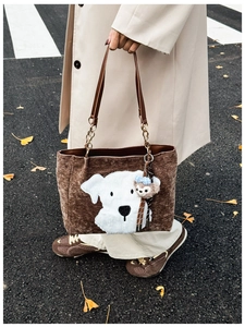 Close-up of brown corduroy tote with a cartoon dog patch and plush toy charm detail