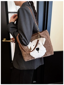 Close-up of brown corduroy tote bag with plush dog applique and metal chain strap