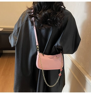 Pink leather crossbody bag with decorative gold chain and cute strawberry charms