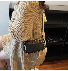 Détail du sac demi-lune en cuir noir avec chaîne dorée et breloque cœur rose