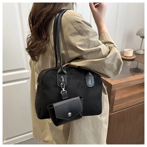 Detail of black suede tote bag with detachable mini envelope charm in home setting