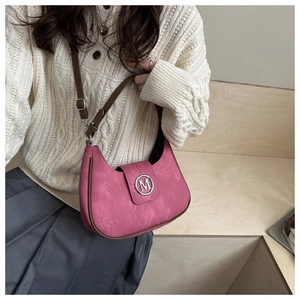 Détail d'un sac bandoulière rose en daim avec boucle métallique M et bordures marron