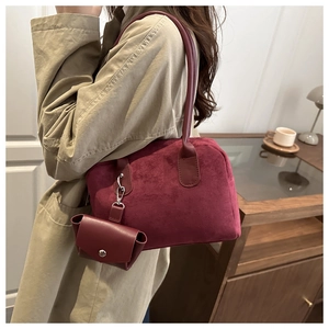 Détail du sac Boston en daim bordeaux avec un mini sac assorti en décoration