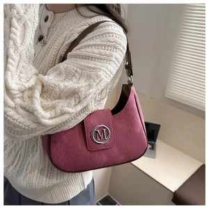 Detail of pink crescent bag with metal M logo buckle and brown leather strap on model