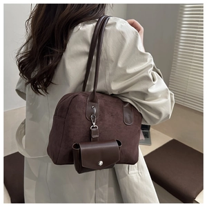 Gros plan sur un sac cabas en suédine marron foncé avec pochette amovible et fermoir argenté