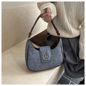 Detail of grey felt crescent bag showing leather strap and metallic M buckle closure