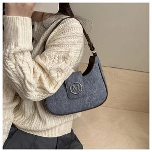 Detail of blue textured hobo bag with brown trim and silver M logo buckle on model