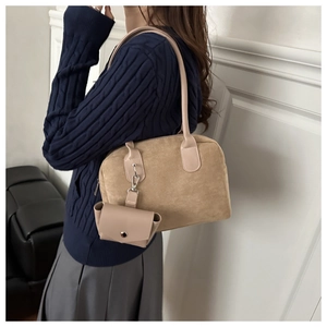 Détail du sac Boston en daim kaki avec mini pochette porté par un mannequin