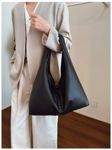 Detailed shot of a black matte soft leather hobo bag worn by a model in a minimalist style