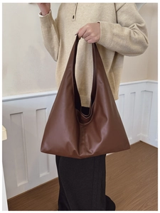Brown faux leather tote bag showcased on shoulder, minimalist aesthetic and large capacity