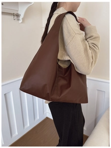 Detail of soft dark brown leather tote bag with natural pleats and minimalist hobo design