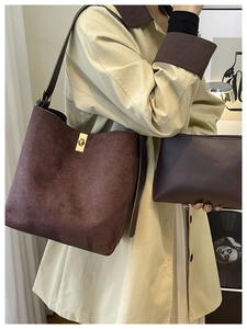 Detail of brown suede bucket bag with gold twist lock and inner pouch on beige trench coat