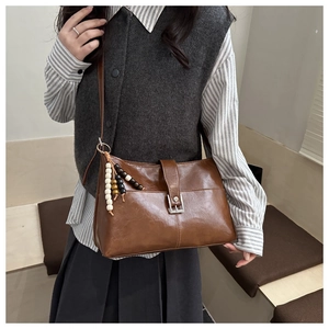 Détail macro du sac cabas en cuir marron avec boucle argentée et pampille de perles décorative