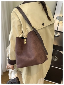 Detail of dark brown matte shoulder bag featuring a metallic swivel lock on a stylish trench coat