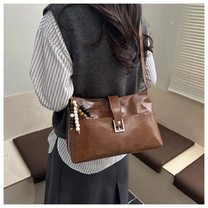 Sac cabas vintage en cuir marron avec breloque en perles vu sous un angle latéral