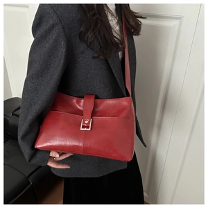 Détail d'un sac cabas rouge vintage porté avec un blazer gris pour un look chic