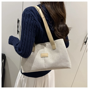 Détail du sac cabas minimaliste en toile crème avec bandoulières en cuir marron
