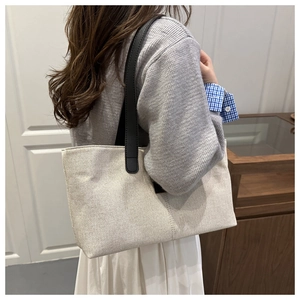 Close-up of minimalist linen tote bag with black leather shoulder straps on a model