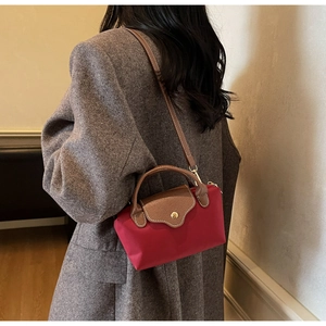 Detailed back view of a mini red nylon and brown leather crossbody bag on a grey coat
