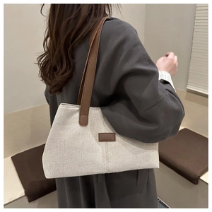 Rear view of model wearing beige canvas tote bag with brown leather straps and detail