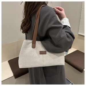 Detail of off-white canvas tote bag with brown leather straps shown on model