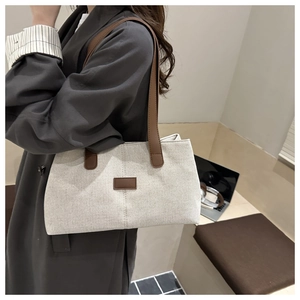 Détail du sac cabas en toile avec lanières brunes et écusson logo dans un décor pro