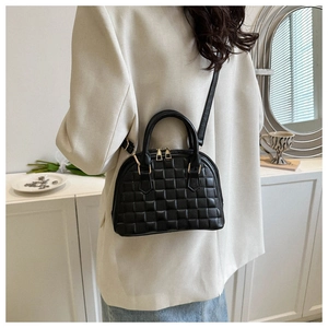Schwarze gesteppte Muscheltasche als Umhängetasche an einem Model in einem Raum