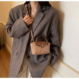 Close-up of a mini nylon dumpling bag with leather trim worn with a grey blazer