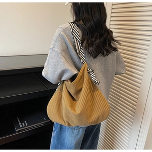 Detailed view of camel corduroy tote bag with striped strap on female model shoulder