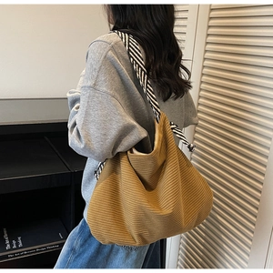 Detail of tan corduroy tote bag showing soft ribbed texture and striped fabric strap