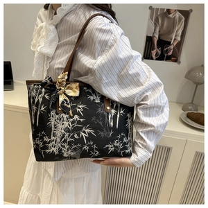 Détail du sac cabas noir à motif bambou avec anses en cuir marron et foulard en soie