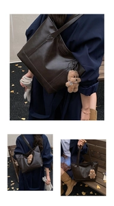 Detail of dark brown leather tote bag with FASHION embossment and plush bear charm